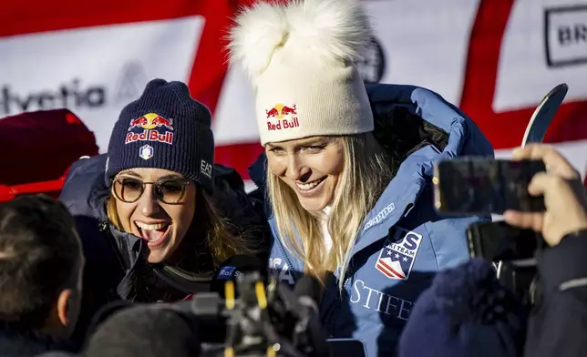 Sofia Goggia of Italy, left, and Lindsey Vonn of United States of America, talk with journalists after completing an alpine ski, women's World Cup super G, in St. Moritz, Switzerland, Saturday, Dec. 21, 2024. (Jean-Christophe Bott/Keystone via AP)