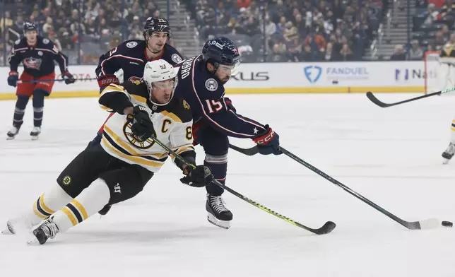 Columbus Blue Jackets' Dante Fabbro, right, clears the puck away from Boston Bruins' Brad Marchand, front left, during the first period of an NHL hockey game Friday, Dec. 27, 2024, in Columbus, Ohio. (AP Photo/Jay LaPrete)