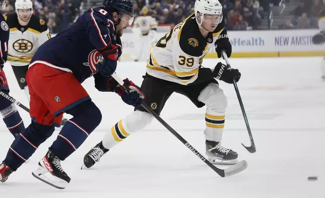 Boston Bruins' Morgan Geekie, right, carries the puck across the blue line as Columbus Blue Jackets' Ivan Provorov, front left, defends during the first period of an NHL hockey game Friday, Dec. 27, 2024, in Columbus, Ohio. (AP Photo/Jay LaPrete)