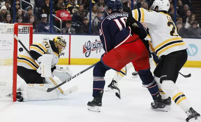 Columbus Blue Jackets' Dmitri Voronkov, center, scores against Boston Bruins' Joonas Korpisalo, left, as Brandon Carlo defends during the second period of an NHL hockey game Friday, Dec. 27, 2024, in Columbus, Ohio. (AP Photo/Jay LaPrete)