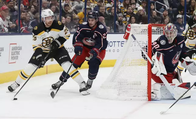 Boston Bruins' Elias Lindholm, left, looks for an open pass as Columbus Blue Jackets' Sean Monahan (23) defends during the first period of an NHL hockey game Friday, Dec. 27, 2024, in Columbus, Ohio. (AP Photo/Jay LaPrete)