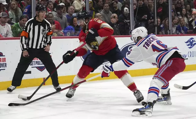 Florida Panthers defenseman Aaron Ekblad, left, controls the puck against New York Rangers center Vincent Trocheck during the first period of an NHL hockey game, Monday, Dec. 30, 2024, in Sunrise, Fla. (AP Photo/Lynne Sladky)