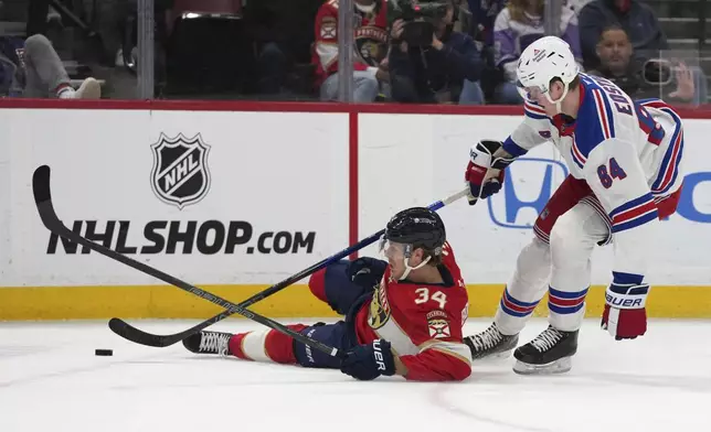 Florida Panthers defenseman Adam Boqvist (34) falls to the ice in front of New York Rangers center Adam Edstrom (84) during the first period of an NHL hockey game Monday, Dec. 30, 2024, in Sunrise, Fla. (AP Photo/Lynne Sladky)