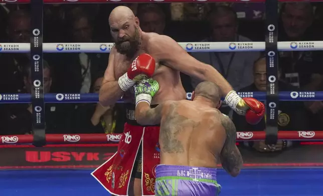 Boxers Britain's Tyson Fury, left, and Ukraine's Oleksandr Usyk compete during their WBA, WBO, and WBC world heavyweight title fight in Riyadh, Saudi Arabia, Saturday, Dec. 21, 2024. (AP Photo/Frank Augstein)