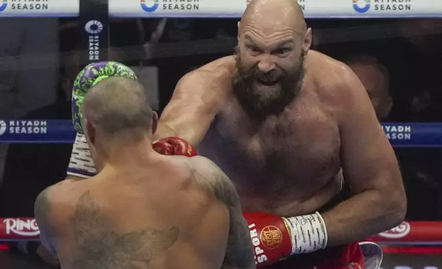 Boxers Britain's Tyson Fury, right, and Ukraine's Oleksandr Usyk compete during their WBA, WBO, and WBC world heavyweight title fight in Riyadh, Saudi Arabia, Saturday, Dec. 21, 2024. (AP Photo/Frank Augstein)