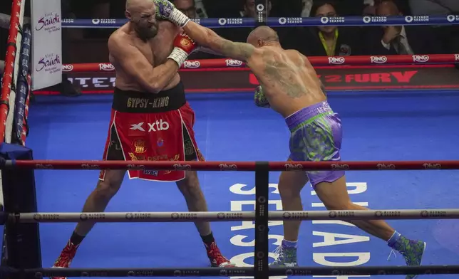 Boxers Britain's Tyson Fury, left, and Ukraine's Oleksandr Usyk compete during their WBA, WBO, and WBC world heavyweight title fight in Riyadh, Saudi Arabia, Saturday, Dec. 21, 2024. (AP Photo/Frank Augstein)