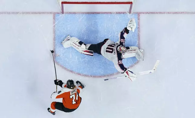 Philadelphia Flyers' Owen Tippett, left, scores the game-winning goal against Columbus Blue Jackets' Elvis Merzlikins during overtime in an NHL hockey game, Saturday, Dec. 21, 2024, in Philadelphia. (AP Photo/Matt Slocum)