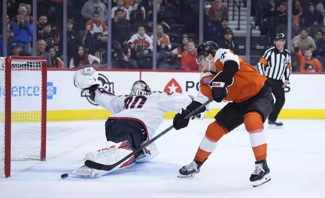 Philadelphia Flyers' Owen Tippett, right, scores the game-winning goal against Columbus Blue Jackets' Elvis Merzlikins during overtime in an NHL hockey game, Saturday, Dec. 21, 2024, in Philadelphia. (AP Photo/Matt Slocum)