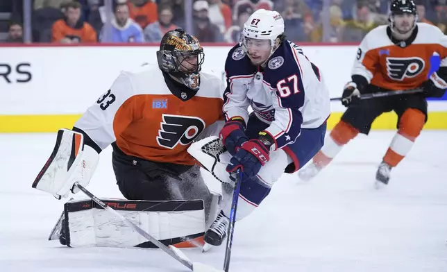 Columbus Blue Jackets' James Malatesta (67) collides with Philadelphia Flyers' Samuel Ersson (33) during the first period of an NHL hockey game, Saturday, Dec. 21, 2024, in Philadelphia. (AP Photo/Matt Slocum)