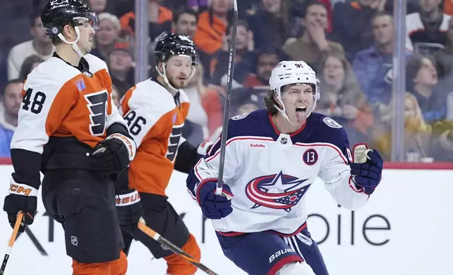 Columbus Blue Jackets' Kent Johnson, right, reacts after assisting on a goal by Mathieu Olivier during the first period of an NHL hockey game against the Philadelphia Flyers, Saturday, Dec. 21, 2024, in Philadelphia. (AP Photo/Matt Slocum)