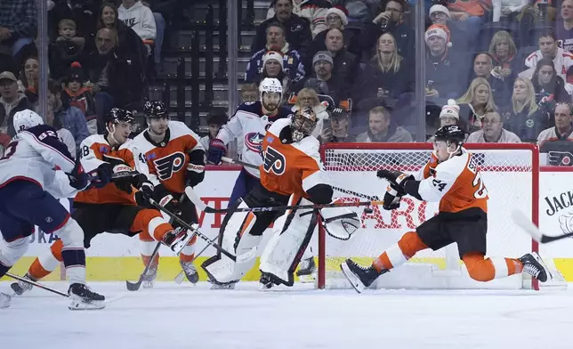 Columbus Blue Jackets' Mikael Pyyhtia (82) scores a goal past Philadelphia Flyers' Nick Seeler (24) and Samuel Ersson (33) during the second period of an NHL hockey game, Saturday, Dec. 21, 2024, in Philadelphia. (AP Photo/Matt Slocum)