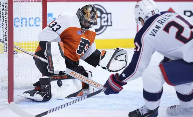 Philadelphia Flyers' Samuel Ersson, left, blocks a shot as Columbus Blue Jackets' James van Riemsdyk skates in during the first period of an NHL hockey game, Saturday, Dec. 21, 2024, in Philadelphia. (AP Photo/Matt Slocum)