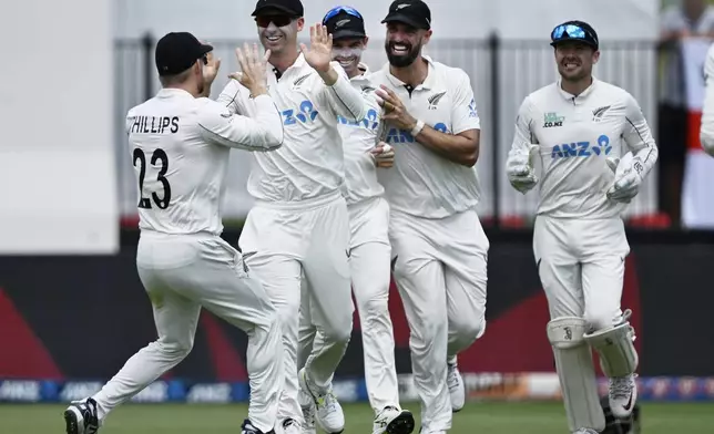 New Zealand players celebrate the wicket of England's Joe Root during play on day two of the third cricket test between England and New Zealand in Hamilton, New Zealand, Sunday, Dec. 15, 2024. (Andrew Cornaga/Photosport via AP)