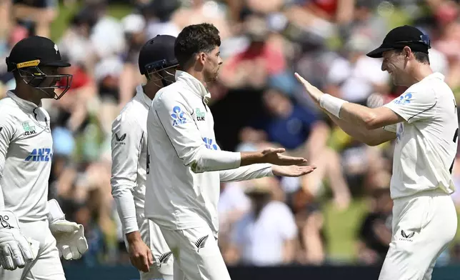New Zealand bowler Mitchell Santner and Matt Henry, right, celebrate the wicket of England's Ollie Pope during play on day two of the third cricket test between England and New Zealand in Hamilton, New Zealand, Sunday, Dec. 15, 2024. (Andrew Cornaga/Photosport via AP)