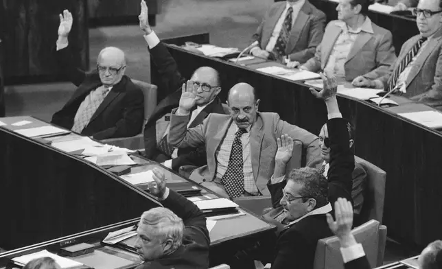 FILE - Israel Minister, counter clockwise from foreground, Ariel Sharon, Agriculture; Ezer Weizman, Defense; Moshe Dayan, Foreign; Yigal Yadin, Deputy Premier; Menachem Begin, Premier; and Simha Erlich, Finance; raise their hands during a vote, ending the parliament session on the U.S. peace proposals for an agreement between Egypt and Israel in Jerusalem, March 22, 1979. (AP Photo/Max Nash, File)