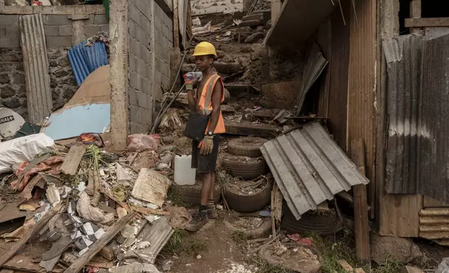 A boy stands amidst debris in the Kaweni slum on the outskirts of Mamoudzou in the French Indian Ocean island of Mayotte, Thursday, Dec. 19, 2024, after Cyclone Chido. (AP Photo/Adrienne Surprenant)