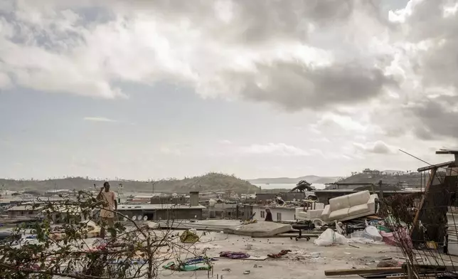 A man stands on his roof in the Kaweni slum on the outskirts of Mamoudzou in the French Indian Ocean island of Mayotte, Thursday, Dec. 19, 2024, after Cyclone Chido. (AP Photo/Adrienne Surprenant)