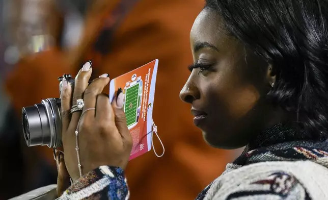 Olympic gymnast Simone Biles uses a camera while watching warmups prior to an NFL football game between the Chicago Bears and the Seattle Seahawks, Thursday, Dec. 26, 2024, in Chicago. (AP Photo/Nam Y. Huh)