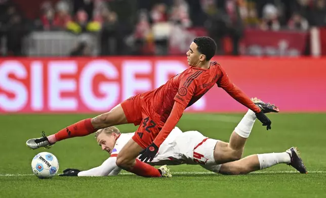 Munich's Jamal Musiala, foreground, vies for the ball against Leipzig's Xaver Schlager during the Bundesliga soccer match between Bayern Munich and RB Leipzig at the Allianz Arena, Munich, Germany, Friday Dec. 20, 2024. (Tom Welle/dpa via AP)