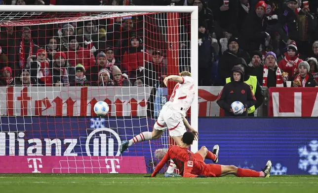 Munich's Jamal Musiala, on the ground, scores during the Bundesliga soccer match between Bayern Munich and RB Leipzig at the Allianz Arena, Munich, Germany, Friday Dec. 20, 2024. (Tom Weller/dpa via AP)