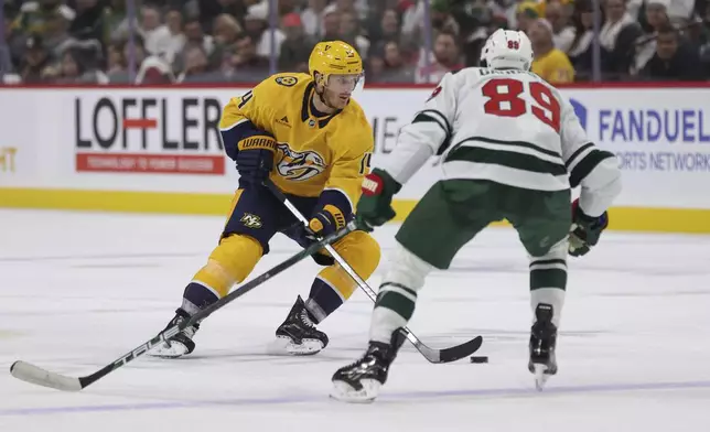 Nashville Predators center Gustav Nyquist (14) skates with the puck while Minnesota Wild center Frederick Gaudreau (89) defends during the second period of an NHL hockey game Saturday, Nov. 30, 2024, in St. Paul, Minn. (AP Photo/Bailey Hillesheim)