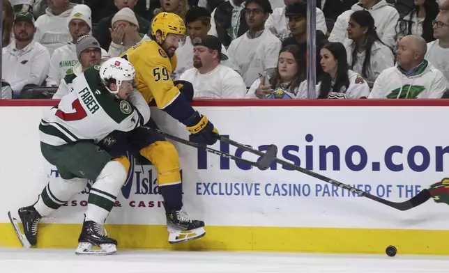 Minnesota Wild defenseman Brock Faber (7) battles for the puck with Nashville Predators defenseman Roman Josi (59) during the second period of an NHL hockey game Saturday, Nov. 30, 2024, in St. Paul, Minn. (AP Photo/Bailey Hillesheim)