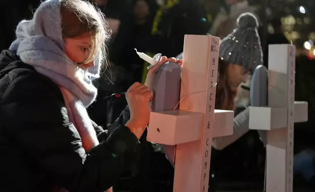 Supporters sign crosses during a candlelight vigil Tuesday, Dec. 17, 2024, outside the Wisconsin Capitol in Madison, Wis., following a shooting at the Abundant Life Christian School on Monday, Dec. 16. (AP Photo/Morry Gash)