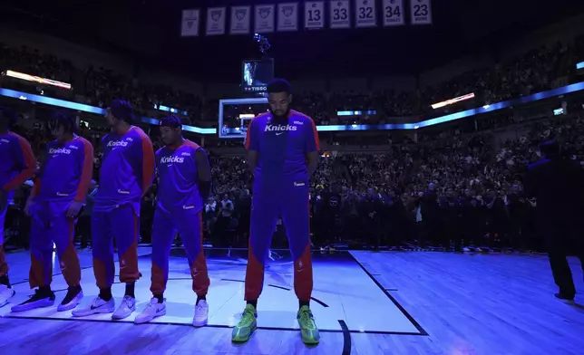 New York Knicks center Karl-Anthony Towns, center, stands on the court as the national anthem is played before an NBA basketball game against the Minnesota Timberwolves, Thursday, Dec. 19, 2024, in Minneapolis. (AP Photo/Abbie Parr)