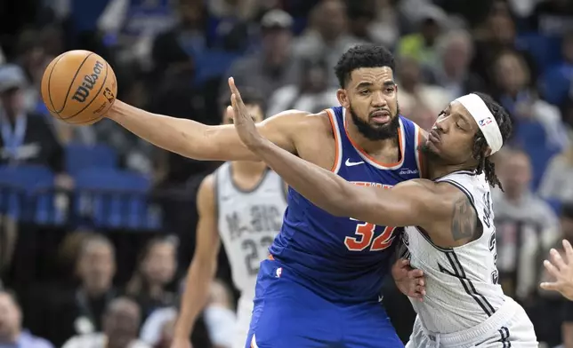 New York Knicks center Karl-Anthony Towns (32) is pressured by Orlando Magic center Wendell Carter Jr., right, during the second half of an NBA basketball game Sunday, Dec. 15, 2024, in Orlando, Fla. (AP Photo/Alan Youngblood)