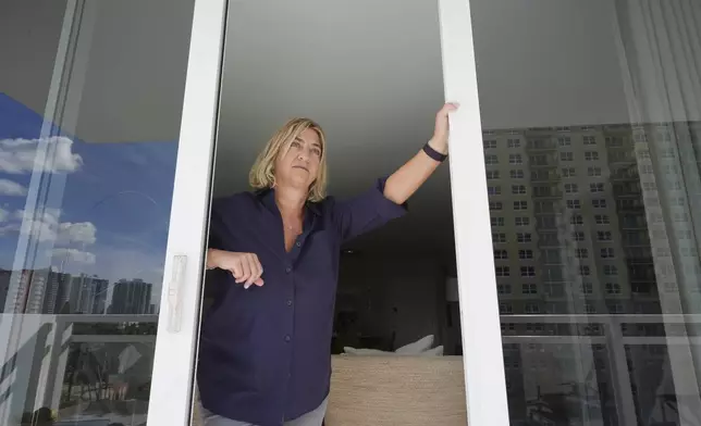 Kelli Roiter, a condo owner in one of the few residential buildings designed in 1971 by architect Morris Lapidus, looks out her balcony at other waterfront high-rise buildings, Thursday, Dec. 5, 2024, in Hallandale Beach, Fla. Roiter supports new rules that require condo associations to maintain reserves and make necessary structural repairs. (AP Photo/Marta Lavandier)