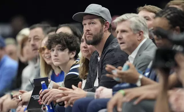 Los Angeles Dodgers pitcher Clayton Kershaw, center, watches play between the Los Angeles Clippers and Dallas Mavericks in the first half of an NBA basketball game in Dallas, Thursday, Dec. 19, 2024. (AP Photo/Tony Gutierrez)