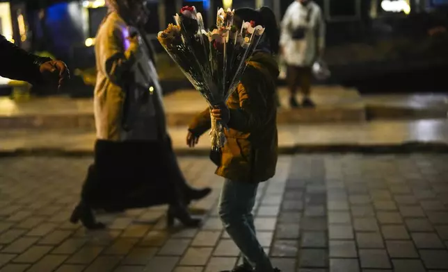 A girl sells flowers to passersby on the Karakoy sea promenade in Istanbul, Turkey, Friday, Dec. 6, 2024. (AP Photo/Francisco Seco)