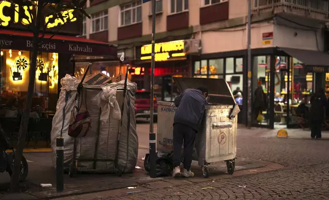 A boy scavenges for items from a trash can in the Kadikoy district in Istanbul, Turkey, Saturday, Dec. 7, 2024. (AP Photo/Francisco Seco)