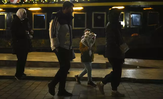 A girl sells flowers to passersby on the Karakoy sea promenade in Istanbul, Turkey, Friday, Dec. 6, 2024. (AP Photo/Francisco Seco)