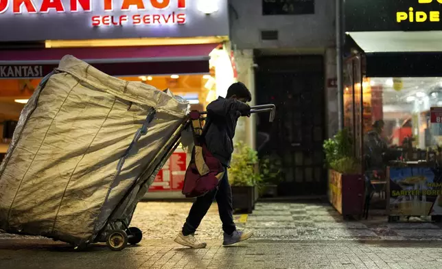 A boy pulls a cart as he scavenges for items in the Kadikoy district in Istanbul, Turkey, Saturday, Dec. 7, 2024. (AP Photo/Francisco Seco)