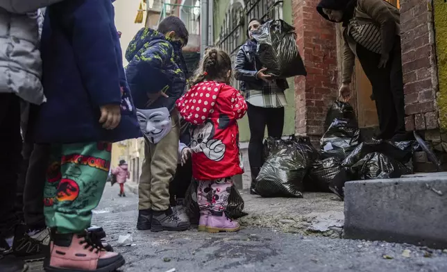 Children and their families wait their turn as coats and shoes are handed out by volunteers in the Tarlabasi neighborhood in Istanbul, Turkey, Saturday, Dec. 14, 2024. (AP Photo/Francisco Seco)