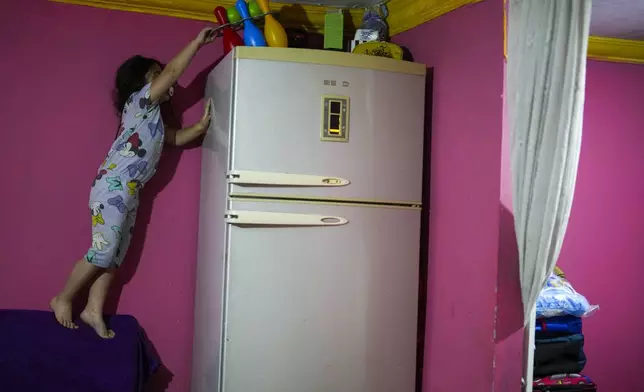 Dilan Sahin, 5, tires to reach her toys in her family's one-room apartment in the Tarlabasi neighborhood in Istanbul, Turkey, Wednesday, Dec. 4, 2024. (AP Photo/Francisco Seco)