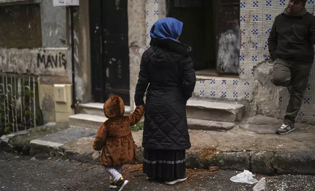 Mehmet Yeralan, 53, a volunteer, talks to a local woman with her child in the Tarlabasi neighborhood in Istanbul, Turkey, Wednesday, Dec. 4, 2024. (AP Photo/Francisco Seco)