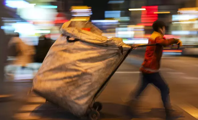 A boy pulls a cart to collect items as he scavenges in the Kadikoy district in Istanbul, Turkey, Monday, Dec. 16, 2024. (AP Photo/Francisco Seco)