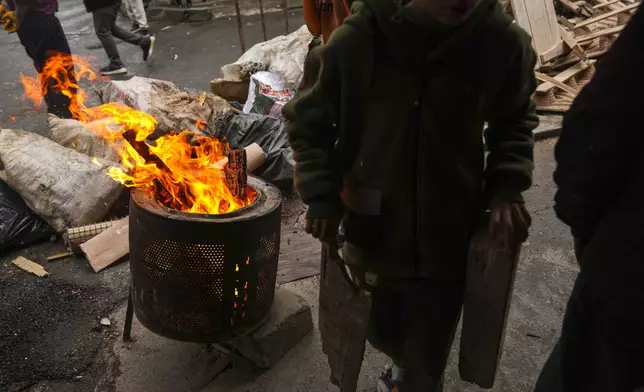 Local boys gather pieces of wood to burn for heat in the Tarlabasi neighborhood in Istanbul, Turkey, Wednesday, Dec. 4, 2024. (AP Photo/Francisco Seco)