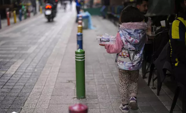 A girl sells plastic items to people in the Kadikoy district in Istanbul, Turkey, Saturday, Dec. 7, 2024. (AP Photo/Francisco Seco)