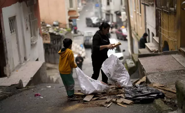 Residents gather pieces of wood to burn for heat in the Tarlabasi neighborhood in Istanbul, Turkey, Wednesday, Dec. 4, 2024. (AP Photo/Francisco Seco)