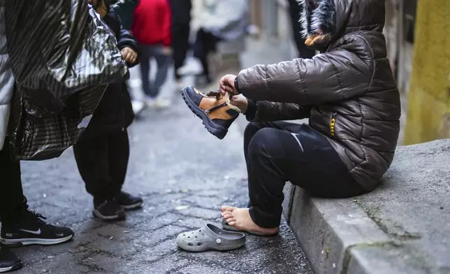 A child tries on a pair of new boots that were handed out by volunteers in the Tarlabasi neighborhood in Istanbul, Turkey, Saturday, Dec. 14, 2024. (AP Photo/Francisco Seco)