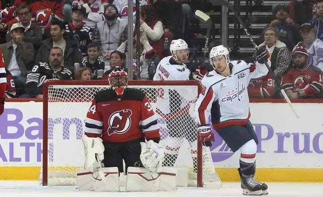 New Jersey Devils goalie Jake Allen, left, and Washington Capitals' Andrew Mangiapane, right, react after Capitals' Jakob Chychrun scored during the second period of an NHL hockey game Saturday, Nov. 30, 2024, in Newark, N.J. (AP Photo/Pamela Smith)