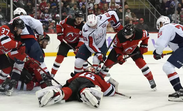 Washington Capitals and New Jersey Devils players fight for the puck as New Jersey Devils goalie Jake Allen, center, attempts to grab it during the first period of an NHL hockey game Saturday, Nov. 30, 2024, in Newark, N.J. (AP Photo/Pamela Smith)