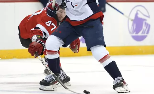 New Jersey Devils' Paul Cotter attempts to steal the puck from Washington Capitals' Rasmus Sandin during the second period of an NHL hockey game Saturday, Nov. 30, 2024, in Newark, N.J. (AP Photo/Pamela Smith)