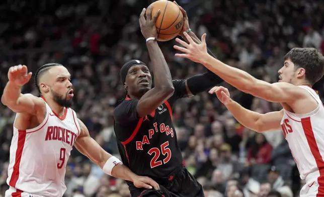 Toronto Raptors forward Chris Boucher (25) is fouled on his way to the hoop between Houston Rockets forward Dillon Brooks (9) and Reed Sheppard, right, during second-half NBA basketball game action in Toronto, Sunday, Dec. 22, 2024. (Frank Gunn/The Canadian Press via AP)