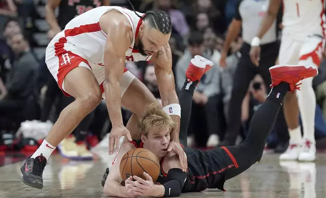 Toronto Raptors guard Gradey Dick, bottom, is fouled by Houston Rockets forward Dillon Brooks, top, as he dives for the ball during first-half NBA basketball game action in Toronto, Sunday, Dec. 22, 2024. (Frank Gunn/The Canadian Press via AP)