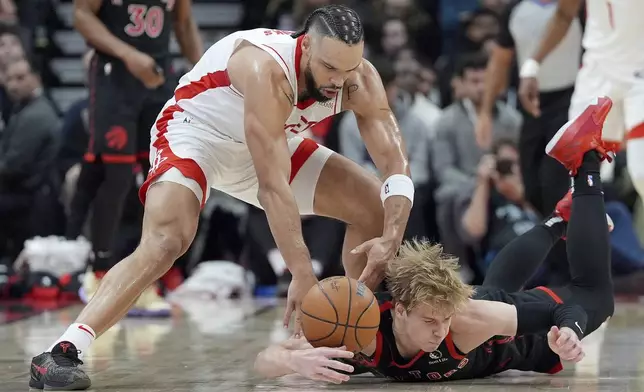 Toronto Raptors guard Gradey Dick, bottom, is fouled by Houston Rockets forward Dillon Brooks, top, as he dives for the ball during first-half NBA basketball game action in Toronto, Sunday, Dec. 22, 2024. (Frank Gunn/The Canadian Press via AP)