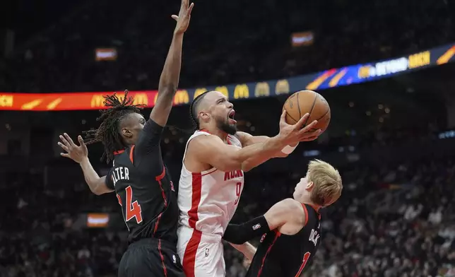 Houston Rockets forward Dillon Brooks (9) picks up an offensive foul as he drives to the net past Toronto Raptors guards Gradey Dick (1) and Ja'Kobe Walter, left, during first-half NBA basketball game action in Toronto, Sunday, Dec. 22, 2024. (Frank Gunn/The Canadian Press via AP)